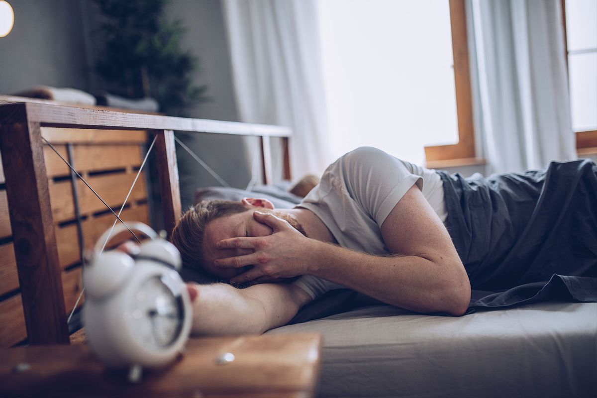 Sleeping man disturbed by alarm clock early in the morning (Getty Images/South_agency)