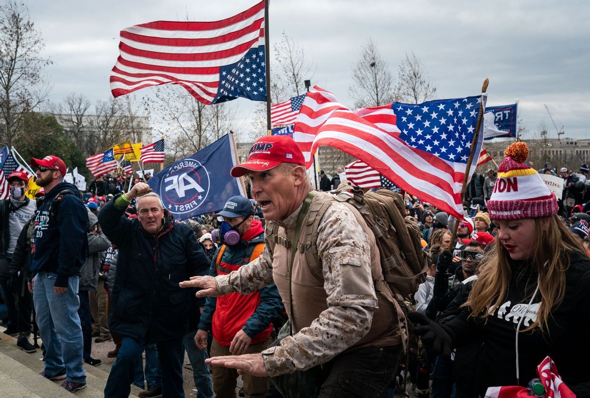 Ray Epps, in the red Trump hat, center, gestures to a line of law enforcement officers, as people gather on the West Front of the U.S. Capitol on Wednesday, Jan. 6, 2021 in Washington, DC. (Kent Nishimura / Los Angeles Times via Getty Images)