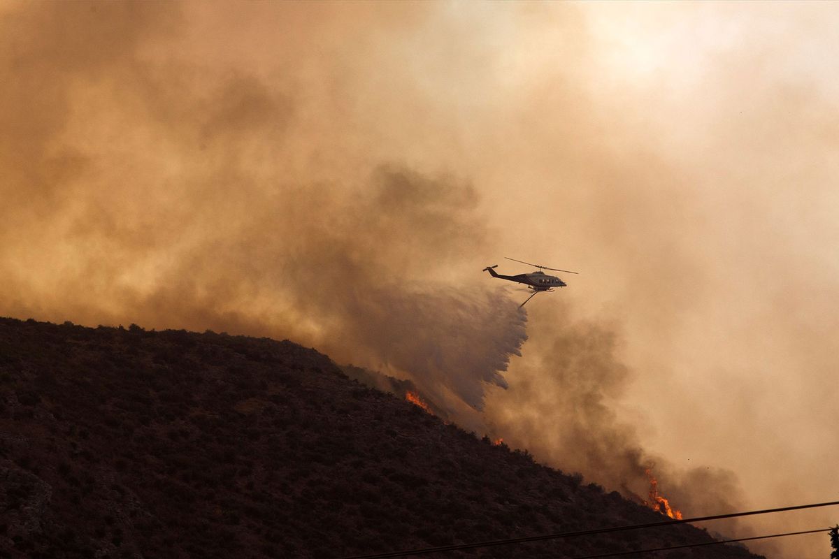 A firefighting helicopter douses a wildfire in Nea Anchialos town, Volos, Greece, on July 27, 2023. (Marios Lolos/Xinhua via Getty Images)