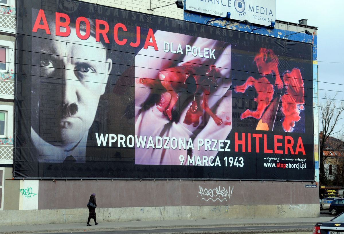 A passerby walks under a huge billboard hung by an anti-abortion group,  with images of Adolf Hitler alongside that of a torn, bloody fetus in the western town of Poznan, Poland, Wednesday, March 3, 2010. The inscription on the billboard  "Abortion for Poles: introduced by Hitler, March 9, 1943." refers to the upcomming anniversary of the introduction of legal abortions in Poland by the Nazi occupying forces during World War II. Today abortion is illegal in Poland. (AP Photo/Remigiusz Sikora)   (Remigiusz Sikora)