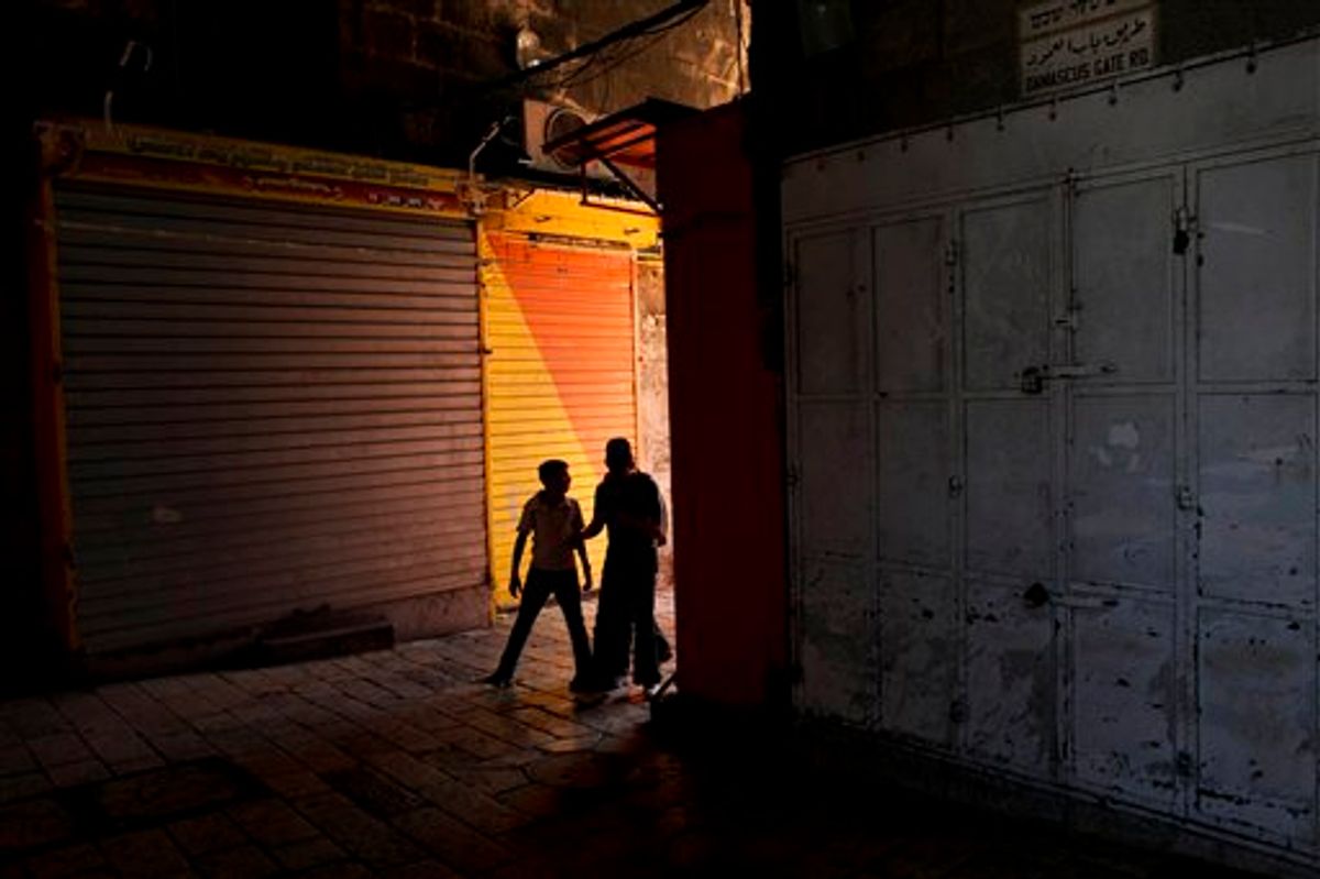 A Palestinian woman and youth pass in front of shops closed as part of a general strike by Palestinians to protest against the Israeli naval commando raid on a flotilla attempting to break the blockade on Gaza, inside Damascus gate, in Jerusalem's Old City, Tuesday, June 1, 2010. Activists seized by Israeli authorities in the deadly raid on a Gaza-bound aid flotilla returned home to European nations Tuesday, including a Turkish woman who brought her one-year-old baby on the voyage. Israel has released some activists, but barred access to others taken off the six boats. (AP Photo/Tara Todras-Whitehill) (AP)