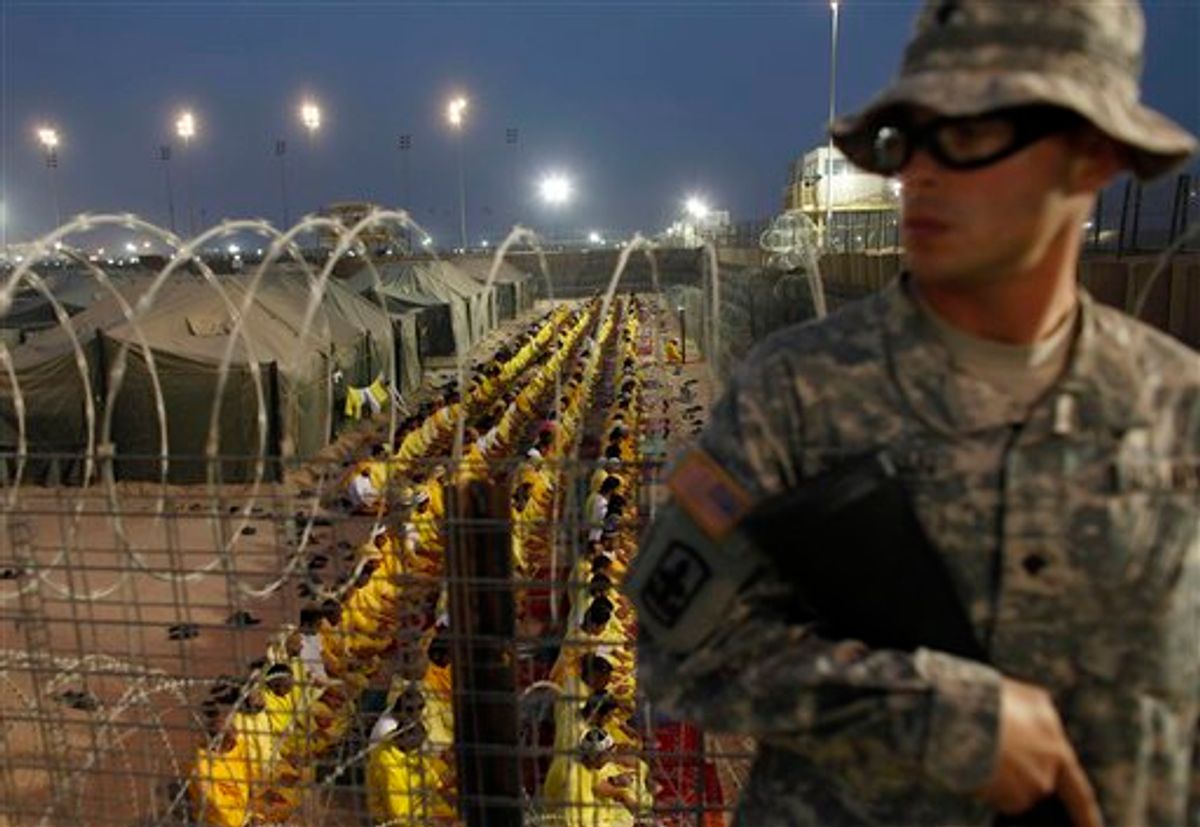 FILE - In this March 16, 2009 file photo, a U.S. soldier stands guard as detainees pray at U.S. military detention facility Camp Bucca, Iraq. A former prison camp that was run by the U.S. military in southern Iraq will be turned into a commercial center with offices, warehouses, aviation and fuel services that will support country's investment activities, an Iraqi official said Monday, Dec. 20, 2010. (AP Photo/Dusan Vranic, File) (AP)