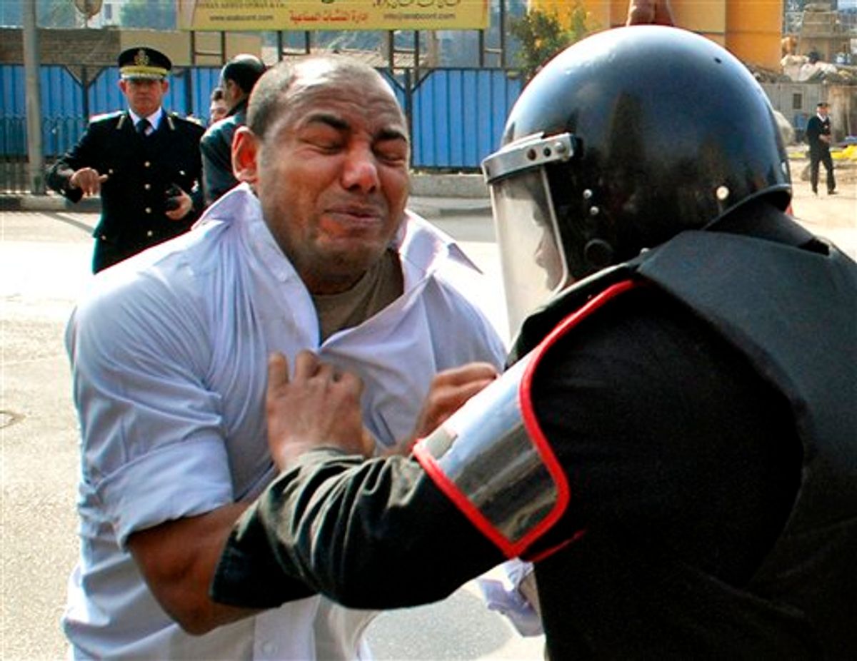 A protester scuffles with a riot policeman as he demonstrates in downtown Cairo, Egypt Tuesday, Jan. 25, 2011. Hundreds of anti-government protesters marched in the Egyptian capital chanting against President Hosni Mubarak and calling for an end to poverty. (AP Photo/Mohammed Abu Zaid) (AP)