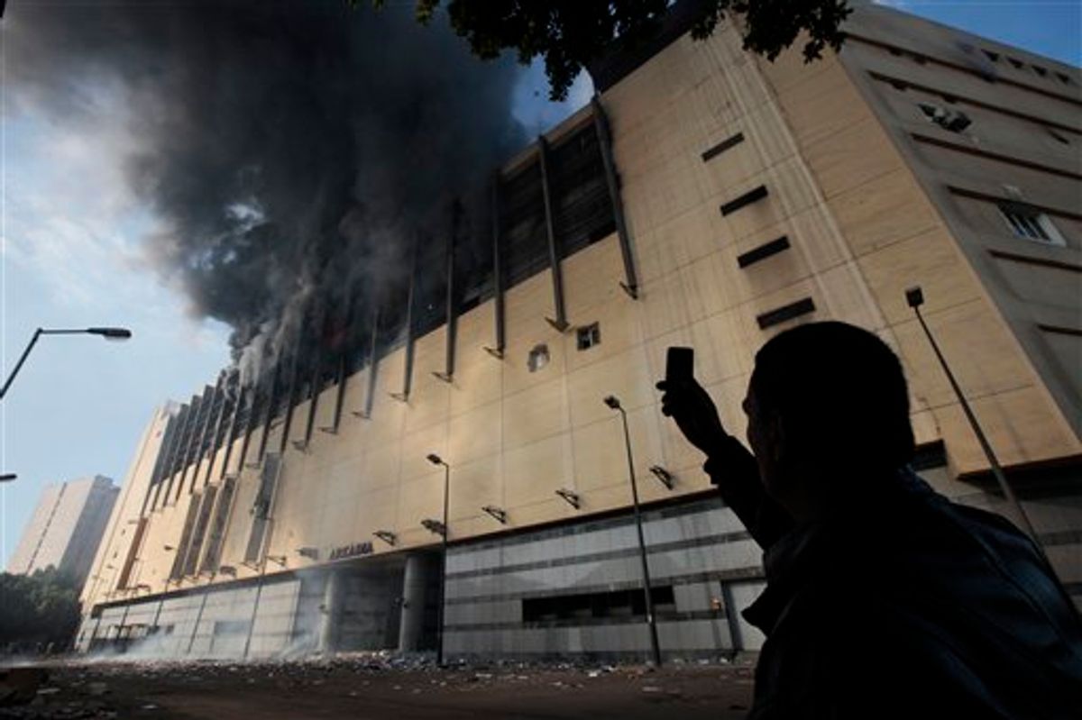 An Egyptian man uses his mobile phone to take a picture of the Arcadia shopping center, that was looted, damaged and set on fire by people in Cairo, Egypt, Sunday Jan. 30, 2011. (AP Photo/Lefteris Pitarakis) (AP)