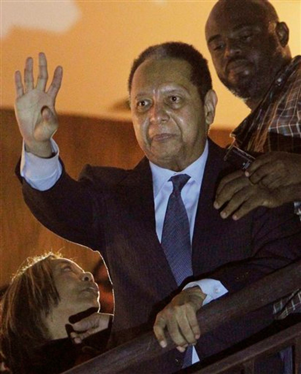 ALTERNATIVE CROP OF PAP109 - Haiti's former dictator Jean-Claude "Baby Doc" Duvalier, center, waves to supporters from a hotel balcony after his arrival in Port-au-Prince, Haiti, Sunday Jan. 16, 2011. Duvalier returned Sunday to Haiti after nearly 25 years in exile, a surprising and perplexing move that comes as his country struggles with a political crisis and the stalled effort to recover from last year's devastating earthquake. (AP Photo/Dieu Nalio Chery) (AP)
