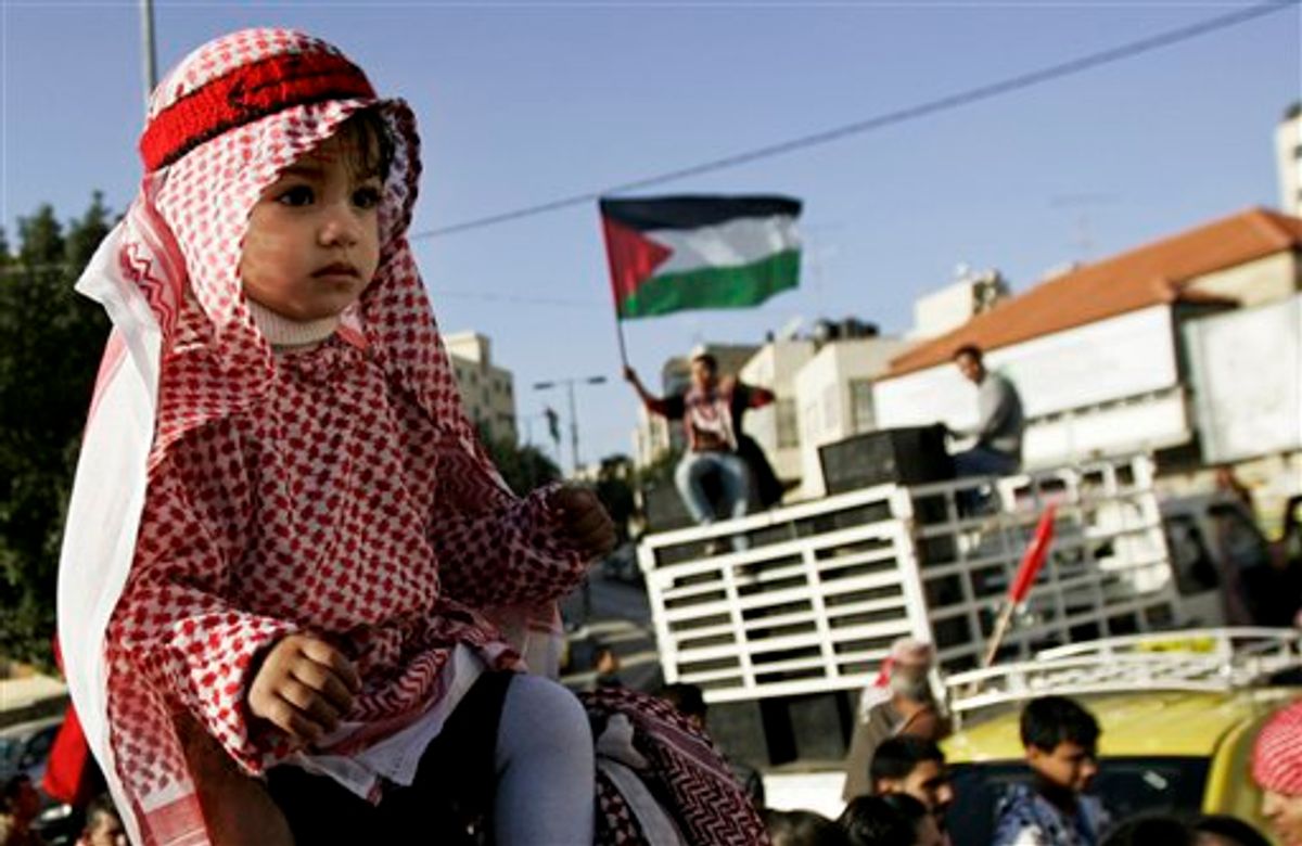 A Palestinian girl sits atop her father's shoulders as a Palestinian flag waves in the background during a march marking the 43rd anniversary of the leftist Popular Front for the Liberation of Palestine (PFLP) in the West Bank city of Ramallah, Saturday, Dec 18, 2010. (AP Photo/Majdi Mohammed) (AP)