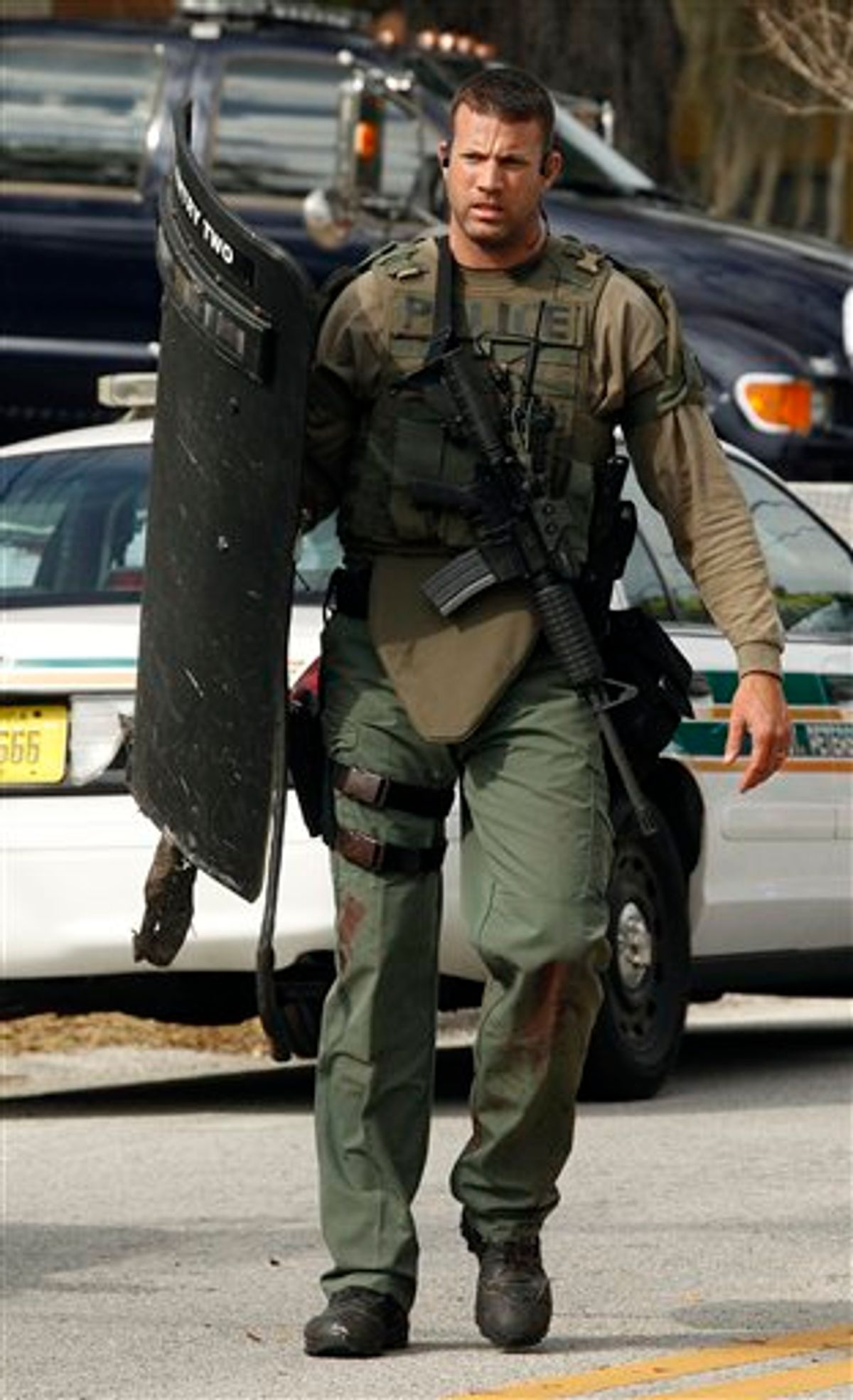 A heavily armed SWAT team member walks away from the scene where three officers were shot Monday, Jan. 24, 2011 in south St. Petersburg, Fla.  Police say a gunman suspected of killing two Florida police officers and wounding a U.S. marshal during a shootout has been found dead. St. Petersburg Police spokesman Michael Puetz says the suspect was found dead when officers went into the home Monday afternoon, about six hours after the shootout. Puetz said officers originally went to the home to arrest 39-year-old Hydra Lacy Jr.  (AP Photo/Chris O'Meara) (AP)