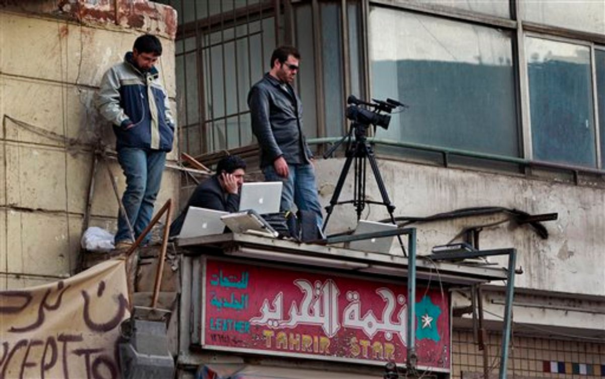 A television cameraman and colleagues standing on the awning of a shop transmit footage by satellite-phone of the continuing protest in Tahrir Square in downtown Cairo, Egypt Monday, Feb. 7, 2011. Egypt's embattled regime announced Monday a 15 percent raise for government employees in an attempt to shore up its base and defuse popular anger but the gestures so far have done little to persuade the tens of thousands of protesters occupying Tahrir Square to end their two-week long protest, leaving the two sides in an uneasy stalemate. Name of shop on sign in arabic reads "Tahrir Star Leather". (AP Photo/Ben Curtis) (AP)
