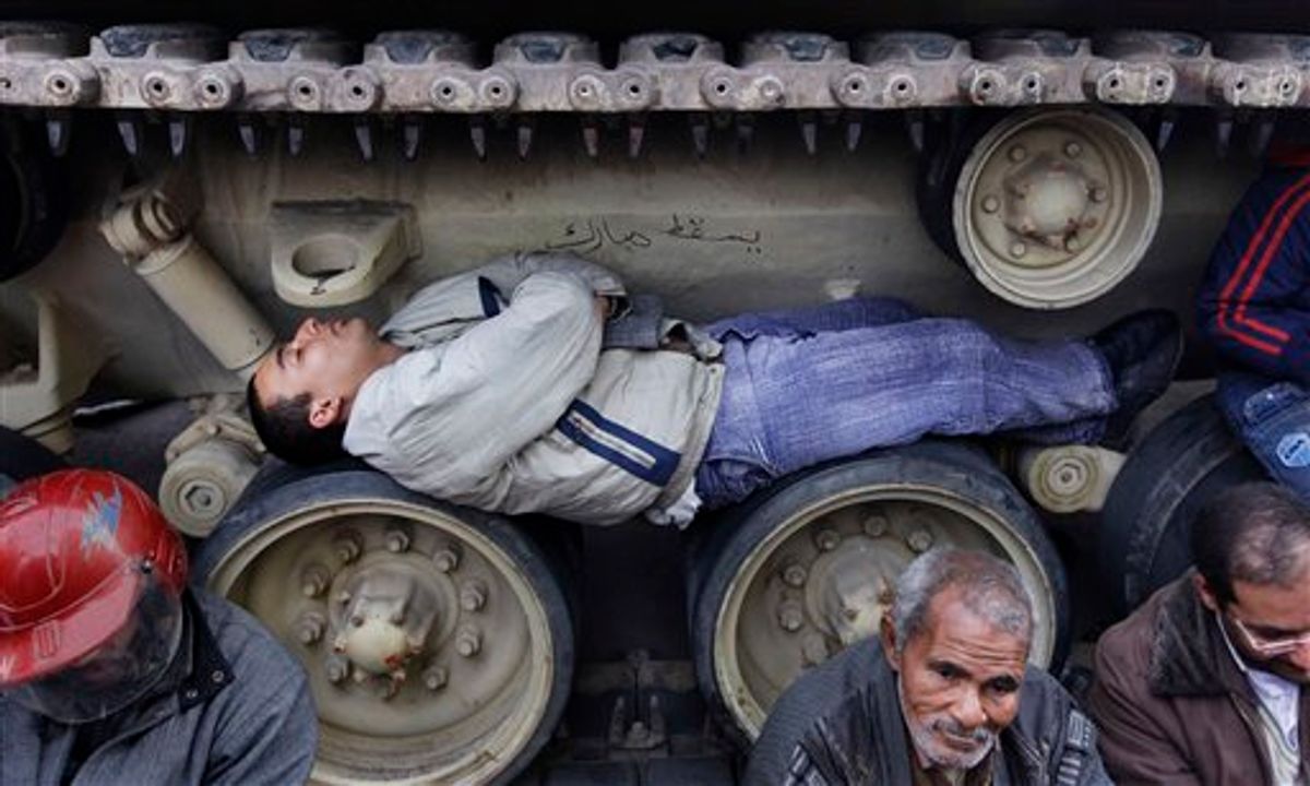 Anti-government protesters sit and lie inside the tracks of an Egyptian Army tank, both to prevent them from moving and to shield themselves from the rain, at the protest site opposite the Egyptian Museum near Tahrir Square in downtown Cairo, Egypt Sunday, Feb. 6, 2011. Egypt's vice president met a broad representation of major opposition groups for the first time Sunday and agreed to allow freedom of the press and to release those detained since anti-government protests began, though Al-Jazeera's English-language news network said one of its correspondents had been detained the same day by the Egyptian military. (AP Photo/Ben Curtis) (AP)