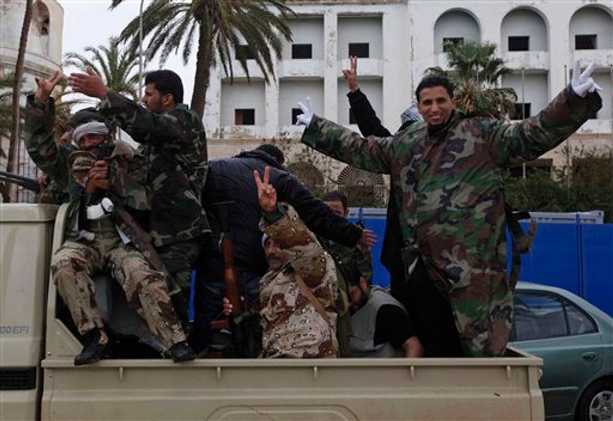 Libyan gunmen flash the V sign as they stand on a military vehicle driving in the streets of  Benghazi, Libya, on Friday Feb. 25, 2011. Several tens of thousands held a rally in support of the Tripoli protesters in the main square of Libya's second-largest city, Benghazi, where the revolt began, about 580 miles (940 kilometers) east of the capital along the Mediterranean coast.  (AP Photo/Hussein Malla) (AP)