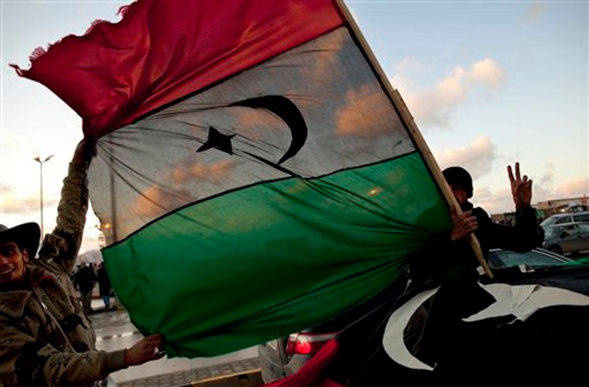 Libyan men hold the former royal flag as they drive past a demonstration against Libyan leader Moammar Gadhafi in Benghazi, in eastern Libya, Sunday, Feb. 27, 2011. (AP Photo/Kevin Frayer) (AP)