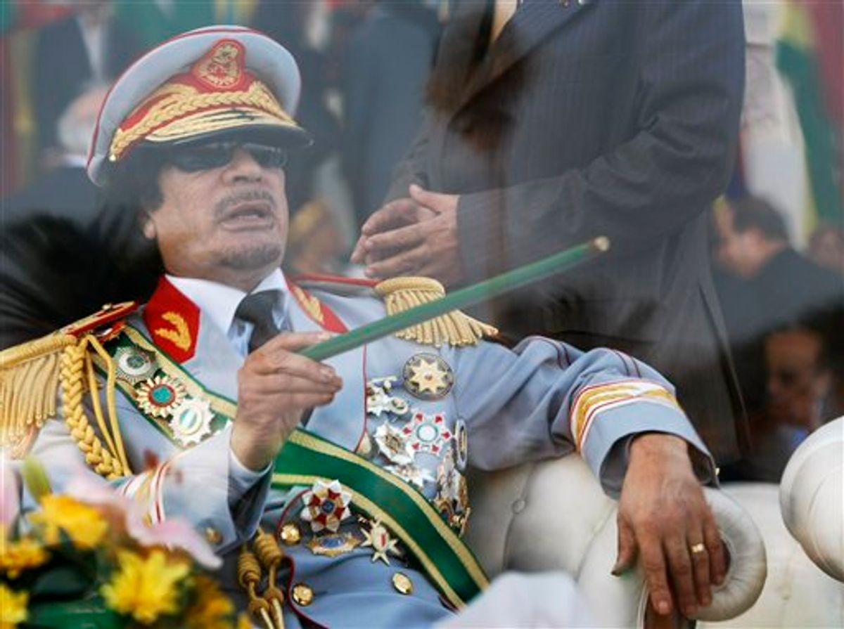 FILE - In this Sept. 1, 2009 file photo, Libyan leader Moammar Gadhafi gestures with a green cane as he takes his seat behind bulletproof glass for a military parade in Green Square, Tripoli, Libya. Libyan protesters celebrated in the streets of Benghazi on Monday, Feb. 21, 2011 claiming control of the country's second largest city after bloody fighting, and anti-government unrest spread to the capital with clashes in Tripoli's main square for the first time. Moammar Gadhafi's son vowed that his father and security forces would fight "until the last bullet." (AP Photo/Ben Curtis, FIle) (AP)