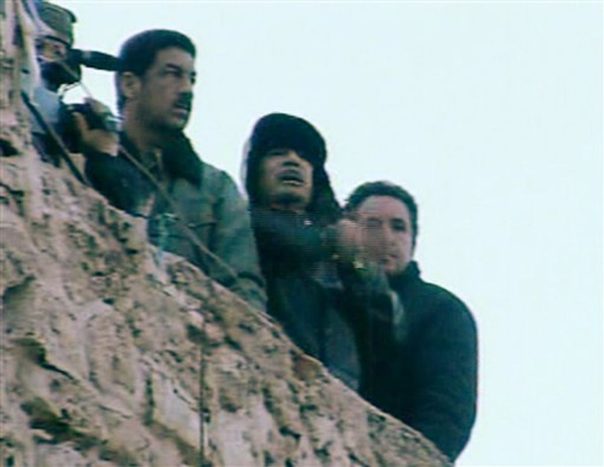 In this image taken from Libya State Television, showing Libyan leader Moammar Gadhafi, centre, as he speaks to followers from the top of a stone wall at The Green Square, central Tripoli, Libya, Friday, Feb. 25, 2011.  The TV station declared this to be a live broadcast from the square and also showed a large crowd celebrating in the square below.  (AP Photo/Libya State) TV OUT (AP)