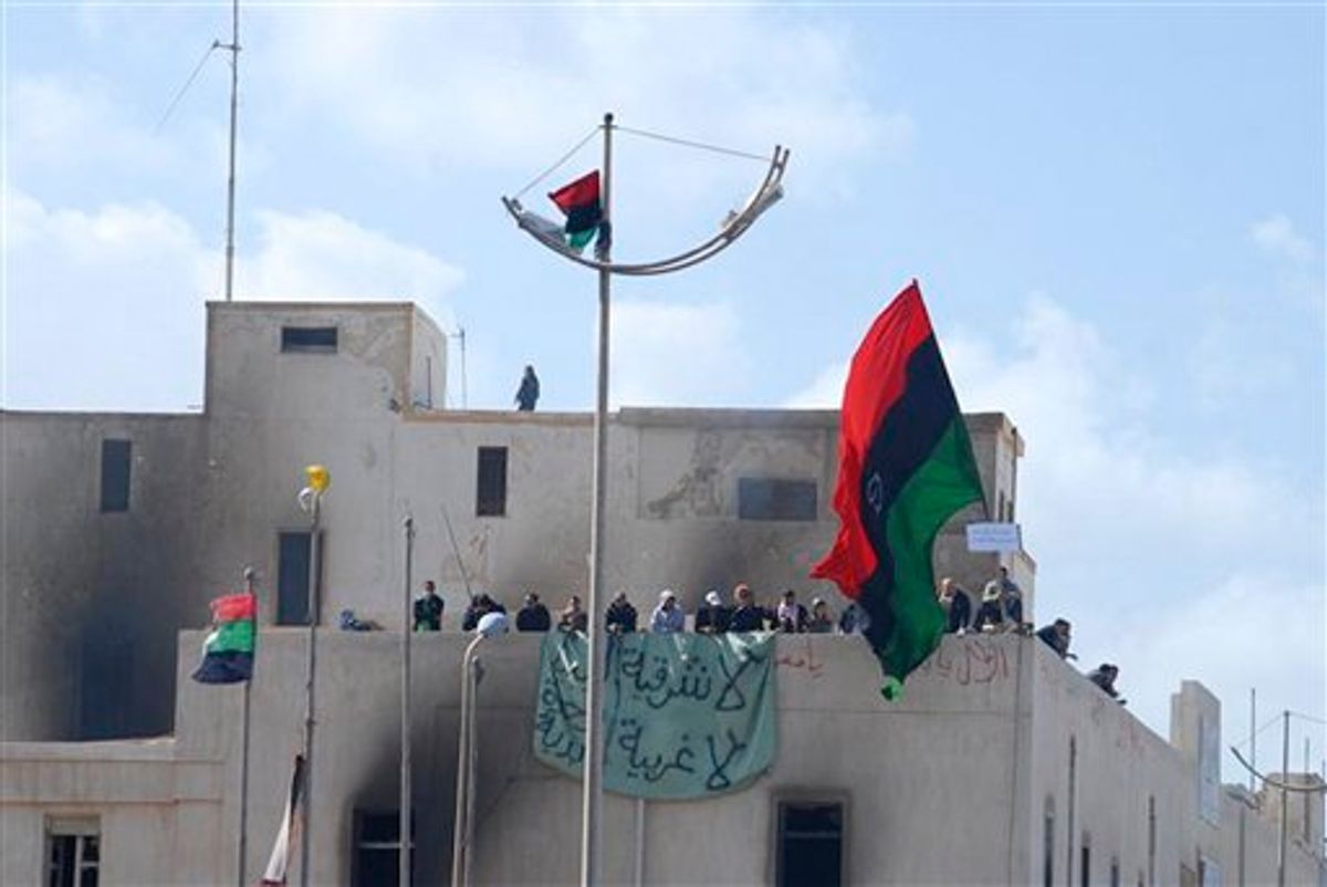 This photograph, obtained by The Associated Press outside Libya and taken by an individual not employed by AP, shows people atop a building holding a banner and a flag during recent days' unrest in Benghazi, Libya. The graffiti in Arabic reads "No to the East, no to the West".  (AP Photo) EDITOR'S NOTE: THE AP HAS NO WAY OF INDEPENDENTLY VERIFYING THE EXACT CONTENT, LOCATION OR DATE OF THIS IMAGE. (AP)