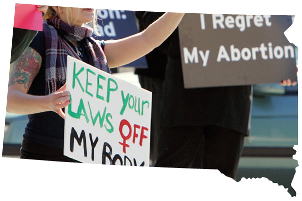 A demonstrator holds up a pro-choice sign, left, as an opposing demonstrator holds up sign reading "I Regret My Abortion", during a rally in downtown Sioux Falls, S.D. 