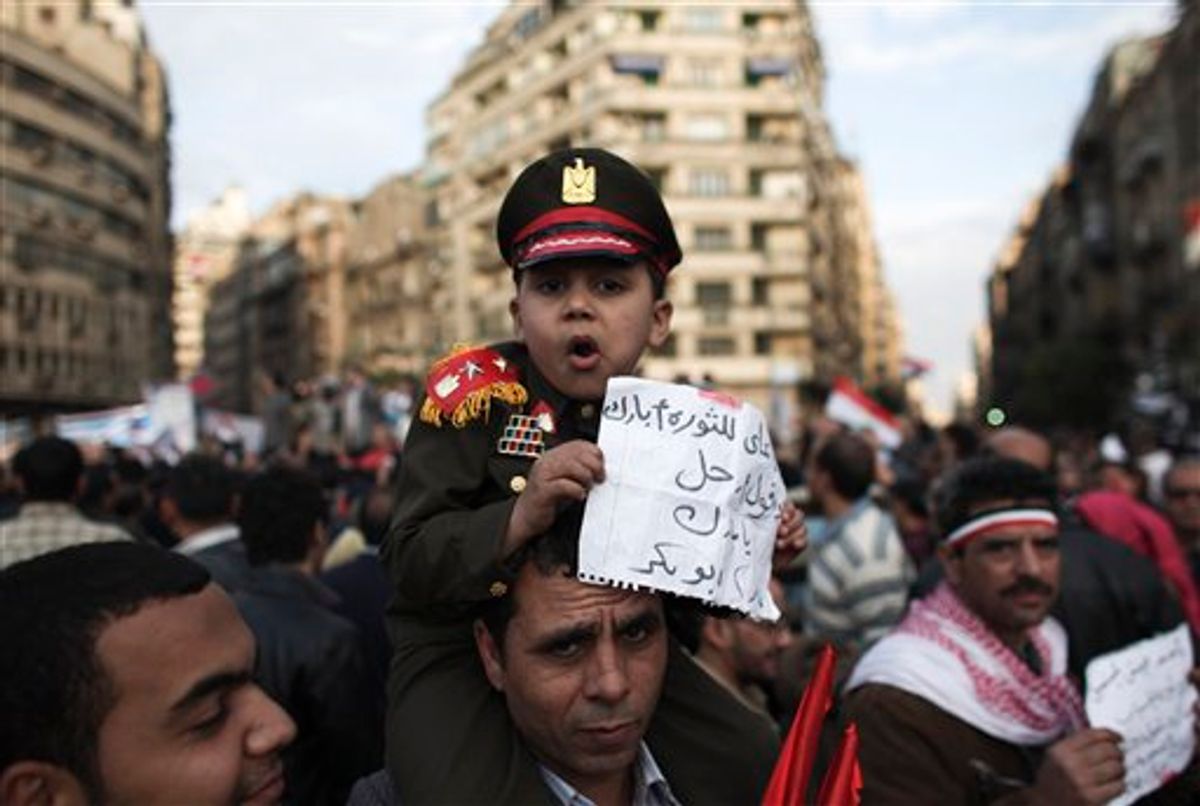 An Egyptian boy dressed as an army colonel sits on his father's shoulders in Tahrir Square in Cairo, Egypt, Thursday, Feb. 10, 2011. President Mubarak refused to step down or leave the country and instead handed his powers to his vice president Thursday, remaining president and ensuring regime control over the reform process, which stunned protesters demanding his ouster, who waved their shoes in contempt and shouted, "Leave, leave, leave." The arabic on the paper reads "I came to give my blessings to the revolution and tell Mubarak to go". (AP Photo/Tara Todras-Whitehill) (AP)