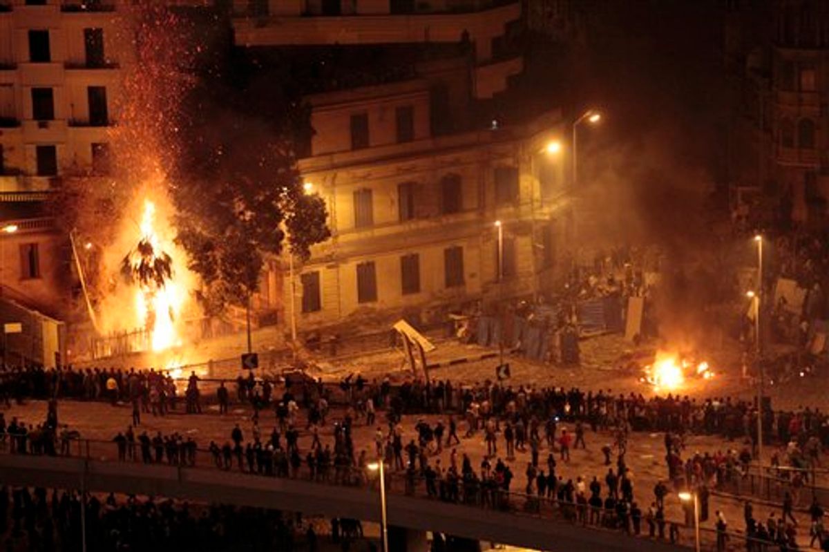 Pro-government demonstrators, bottom, clash with anti-government demonstrators, top right, as a palm tree burns from a firebomb, in Tahrir Square, the center of anti-government demonstrations, in Cairo, Egypt, early Thursday, Feb. 3, 2011. Thousands of supporters and opponents of Egyptian President Hosni Mubarak battled in Cairo's main square all day Wednesday, raining stones, bottles and firebombs on each other in scenes of uncontrolled violence as soldiers stood by without intervening. Government backers galloped in on horses and camels, only to be dragged to the ground and beaten bloody. (AP Photo/Lefteris Pitarakis) (AP)