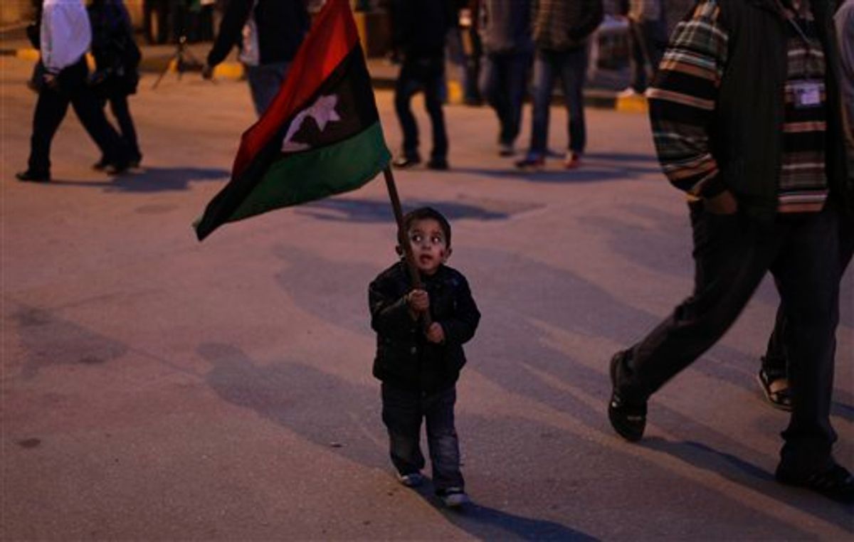 A Libyan child walks with a Libyan pre-Gadhafi flag during an evening  demonstration in Benghazi, Libya, Wednesday, March 30, 2011. Rebels retreated Wednesday from the key Libyan oil port of Ras Lanouf along the coastal road leading to the capital Tripoli after they came under heavy shelling from ground forces loyal to leader Moammar Gadhafi.  (AP Photo/Altaf Qadri) (AP)