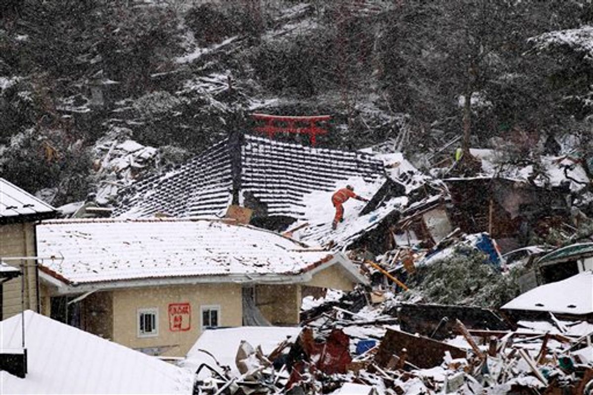 A member of a British search and rescue team climbs on the roof of a building damaged by the tsunami, whilst searching for trapped people as snow falls in Kamaishi, Japan, Wednesday, March 16, 2011. Two search and rescue teams from the U.S. and a team from the U.K. with combined numbers of around 220 personnel searched the town for survivors Wednesday to help in the aftermath of the earthquake and tsunami. (AP Photo/Matt Dunham) (AP)