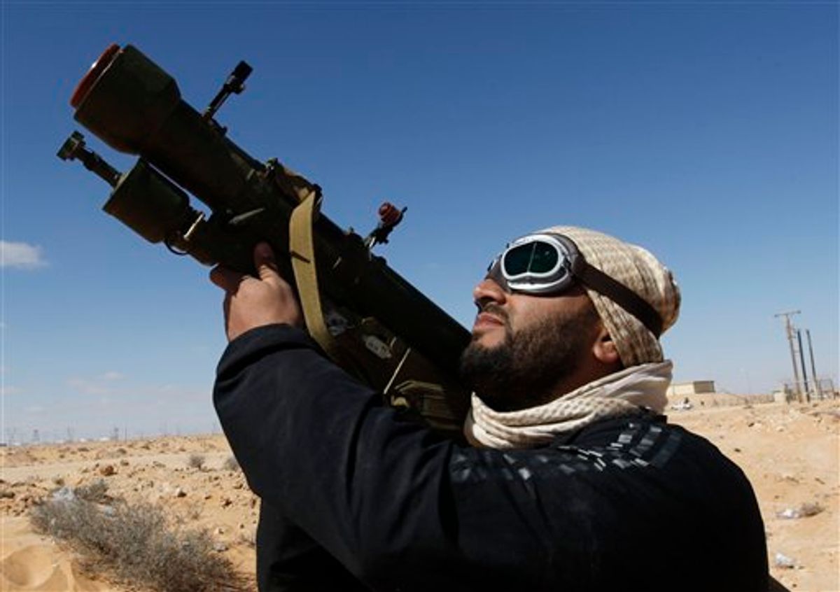 An anti-Libyan leader Moammar Gadhafi rebel, holds his anti-aircraft missile as he looks to the sky, in the oil town of Ras Lanouf, eastern Libya, Sunday, March 6, 2011. Thousands of Moammar Gadhafi's supporters poured into the streets of Tripoli on Sunday, waving flags and firing their guns in the air in the Libyan leader's main stronghold. Earlier, the city woke to the crackle of heavy machine-gun fire that rattled the capital before dawn.(AP Photo/Hussein Malla) (AP)