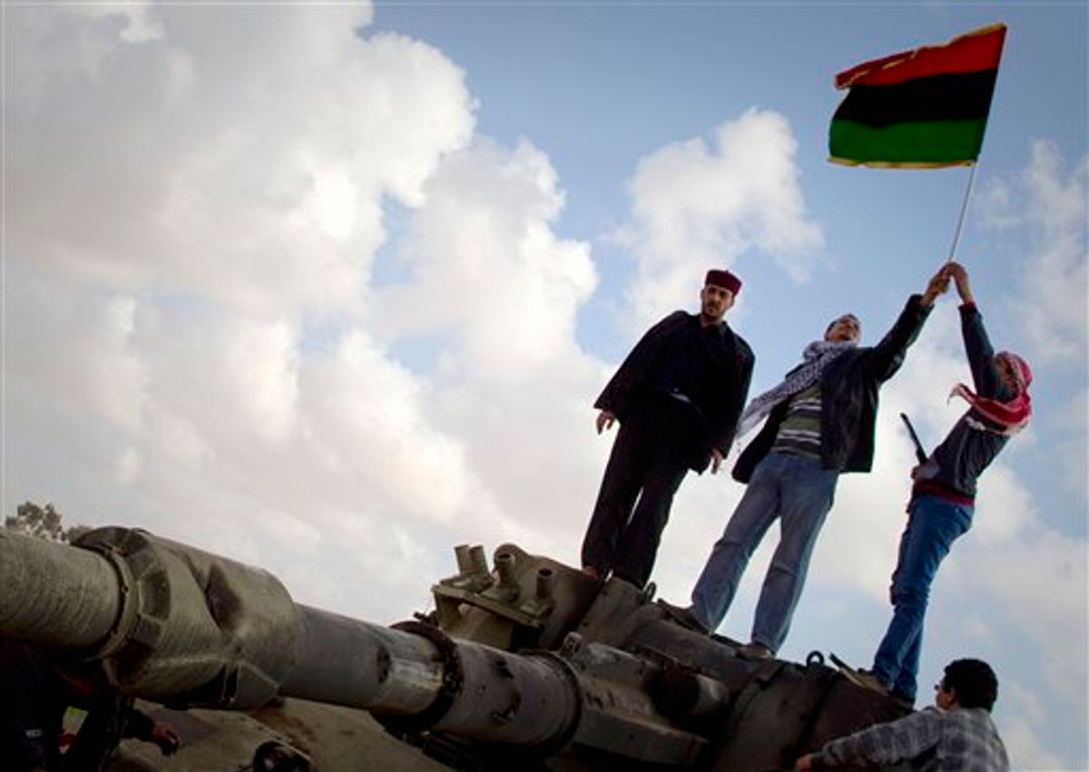 Libyan men celebrates on a destroyed tank belonging to the forces of Moammar Gadhafi in the outskirts of Benghazi, eastern Libya, Sunday, March 20, 2011. The tanks were destroyed earlier by U.S. and allied airstrikes.  (AP Photo/Anja Niedringhaus) (AP)