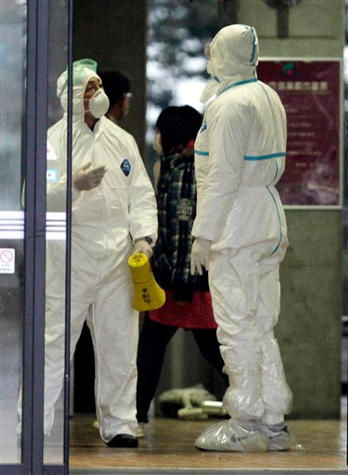 Officials wearing protective suits chat as they usher people through a radiation emergency scanning center in Koriyama, Japan, Tuesday, March 15, 2011 four days after a giant quake and tsunami struck the country's northeastern coast. (AP Photo/Mark Baker) (AP)