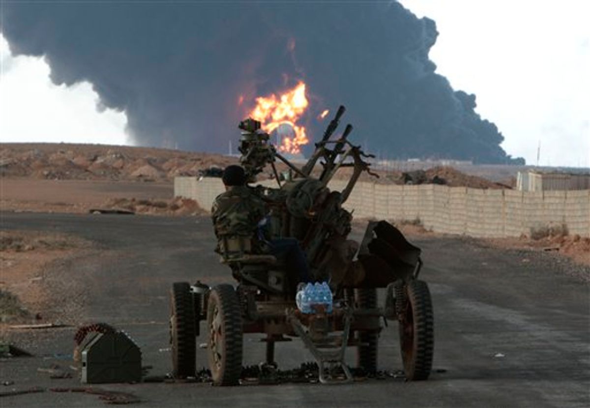 Anti-Libyan Leader Moammar Gadhafi rebel, mans an anti-aircraft machine gun, as a pall of smoke and flames rises from a fuel storage depot that was attacked during fighting against pro-Moammar Gadhafi fighters, in Sedra, eastern Libya, on Wednesday March 9, 2011. Gadhafi appears to be keeping up the momentum he has seized in recent days in his fight against rebels trying to move on the capital, Tripoli, from territory they hold in eastern Libya. (AP Photo/Hussein Malla) (AP)