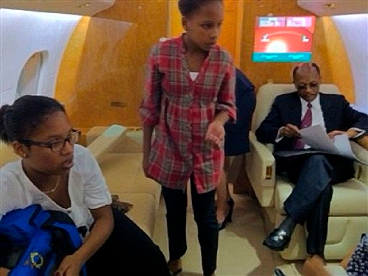 In this photo released by the Democracy Now! TV and radio show on Thursday March 17, 2011, the former President of Haiti, Jean Bertrand Aristide, right, sits inside on an airplane with daughters Michaela, 12, left, and Christine, 14, moments before takeoff in Johannesburg, South Africa, Thursday March 17, 2011.   Aristide, who was forced to flee Haiti due to a rebellion in 2004 aboard a U.S. plane, will return after seven years of exile in South Africa, days before Haiti's presidential runoff election Sunday. (AP Photo/Amy Goodman/DemocracyNow.org) (AP)