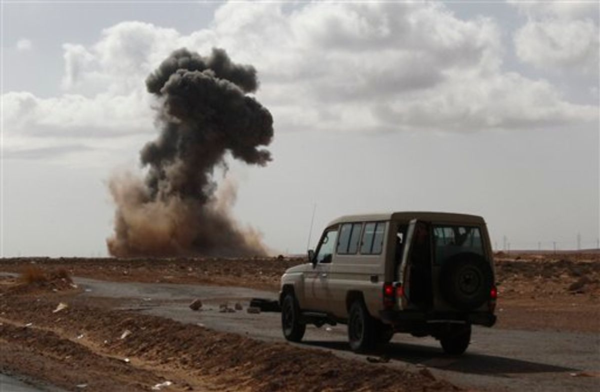 Anti-Gadhafi rebels drive a vehicle forward as smoke rises following an air strike by pro-Libyan leader Moammar Gadhafi warplanes that attacked a highway leading to the town of Ras Lanouf, eastern Libya, Tuesday, March 8, 2011. Libyan warplanes launched at least three new airstrikes Tuesday near rebel positions in the oil port of Ras Lanouf, keeping up a counteroffensive to prevent the opposition from advancing toward leader Moammar Gadhafi's stronghold in the capital Tripoli. (AP Photo/Hussein Malla) (AP)