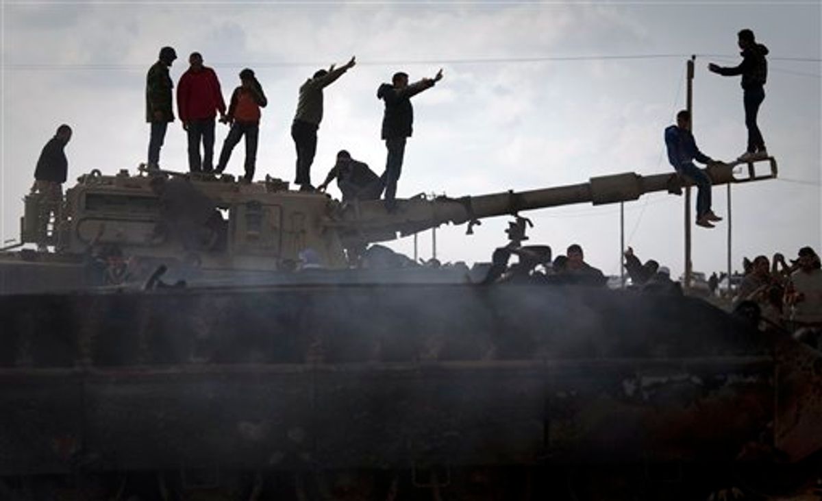 Libyan people celebrate on a tank belonging to the forces of Moammar Gadhafi in the outskirts of Benghazi, eastern Libya, Sunday, March 20, 2011. The tanks were destroyed earlier by NATO plans. (AP Photo/Anja Niedringhaus) (AP)