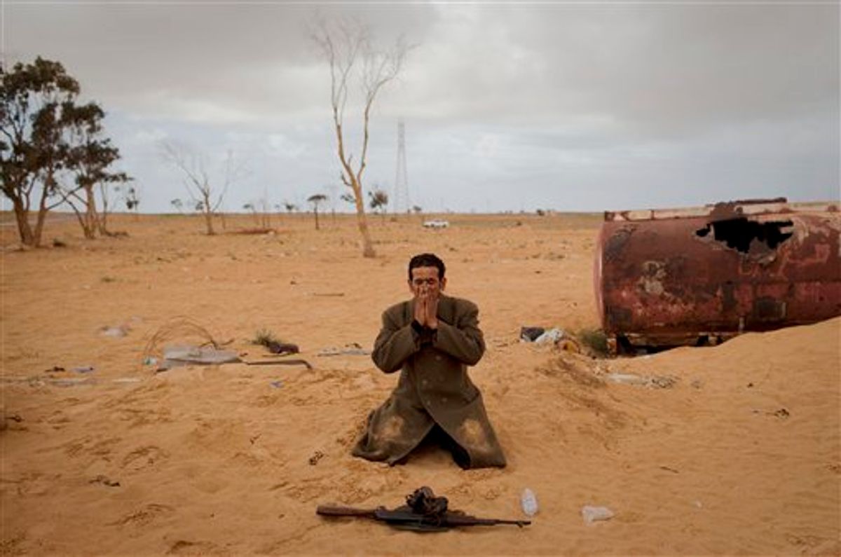 A Libyan rebel prays next to his gun on the frontline of the outskirts of the city of Ajdabiya, south of Benghazi, eastern Libya, Monday, March 21, 2011. The international military intervention in Libya is likely to last "a while," a top French official said Monday, echoing Moammar Gadhafi's warning of a long war ahead as rebels, energized by the strikes on their opponents, said they were fighting to reclaim a city under siege from the Libyan leader's forces.(AP Photo/Anja Niedringhaus) (AP)