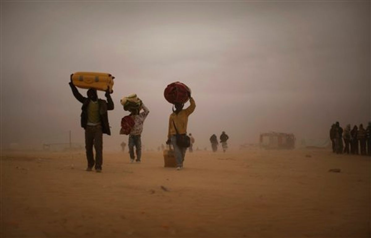 Men, who used to work in Libya and fled the unrest in the country, carry their belongings as they walk during a sand storm in a refugee camp at the Tunisia-Libyan border, in Ras Ajdir, Tunisia, Tuesday, March 15, 2011. More than 250,000 migrant workers have left Libya for neighboring countries, primarily Tunisia and Egypt, in the past three weeks. (AP Photo/Emilio Morenatti) (Associated Press)