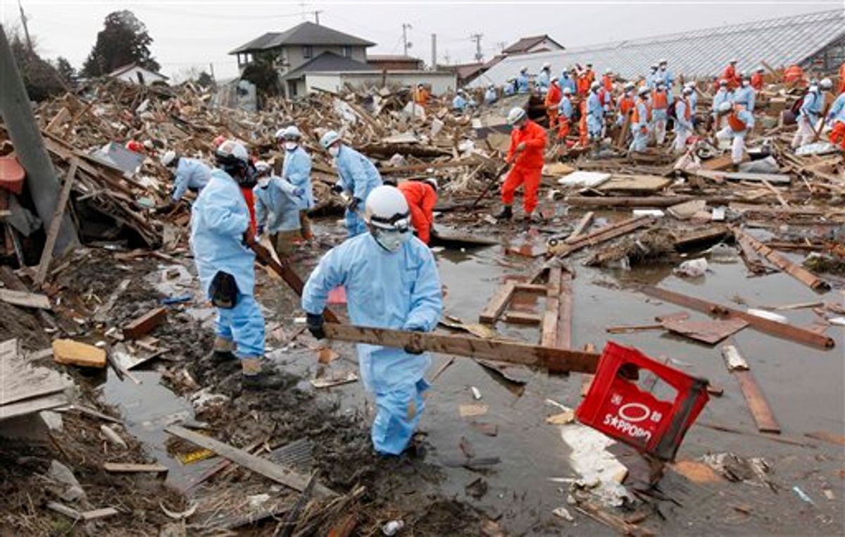 Rescuers sift through the remains of a property in the suburb of Natori, Miyagi Prefecture, Japan, Sunday, March 20, 2011 after the March 11 earthquake and tsunami devastated the area. (AP Photo/Mark Baker) (AP)