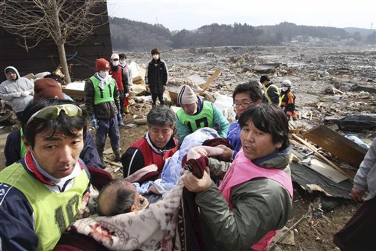 CORRECTS PREFECTURE (STATE) - Rescue workers carry an elderly man found alive by tsunami survivors buried under rubble along a slope of a hill in Minamisanrikucho in Miyagi Prefecture (state) Monday, March 14, 2011, three days after a powerful earthquake-triggered tsunami hit the country's northeast coast. (AP Photo/The Yomiuri Shimbun, Hiroaki Ohno) JAPAN OUT, CREDIT MANDATORY (AP)