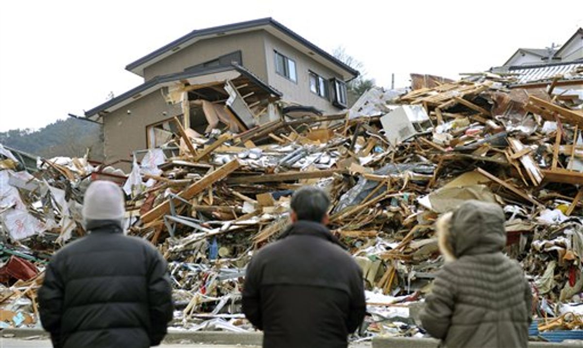 Family members stand in front of their collapsed house in Onagawa, northern Japan Friday, March 18, 2011, one week after a massive earthquake and tsunami.  (AP Photo/Kyodo News) JAPAN OUT, MANDATORY CREDIT, NO LICENSING IN CHINA, HONG KONG, JAPAN, SOUTH KOREA AND FRANCE (AP)