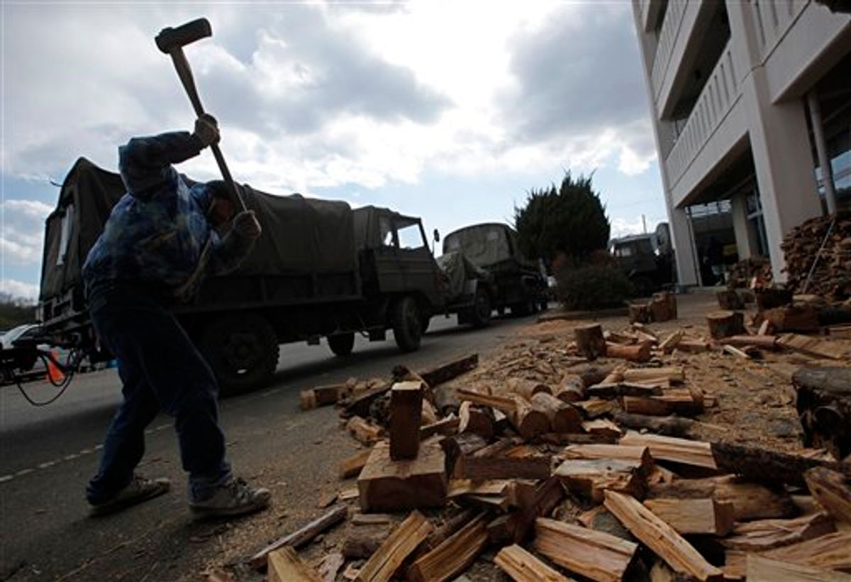 A survivor cuts woods for fire to warm at a shelter in the devastated town of Yamamoto, Miyagi Prefecture, northeastern Japan, Monday, March 28, 2011. The March 11 quake off Japan's northeast coast triggered a tsunami that barreled onshore and disabled the Fukushima nuclear complex. (AP Photo/Vincent Yu) (AP)