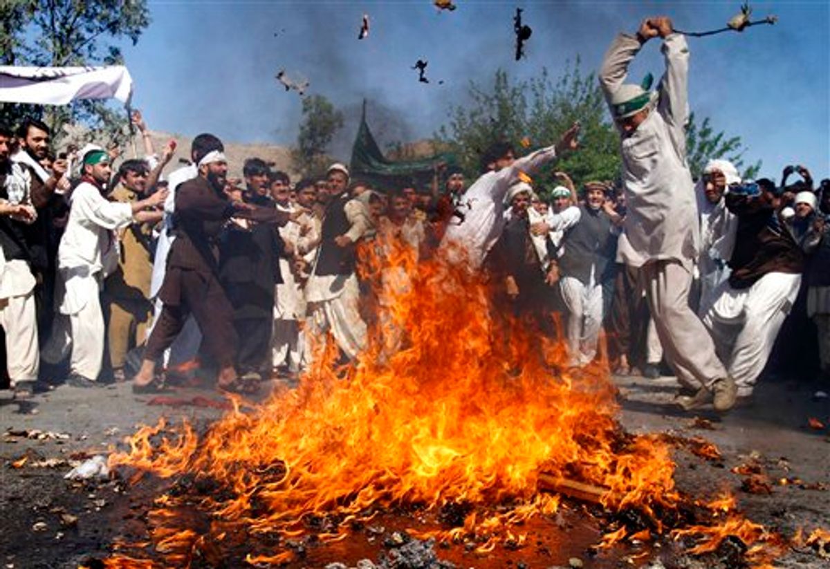 An Afghan protestor beats a burning effigy of U.S. President Barack Obama during a rally in Jalalabad, Afghanistan on Sunday, April 3, 2011. Afghan protests against the burning of a Quran in Florida entered a third day with a demonstration in the major eastern city Sunday, while the Taliban called on people to rise up, blaming government forces for any violence. (AP Photo/Rahmat Gul) (AP)