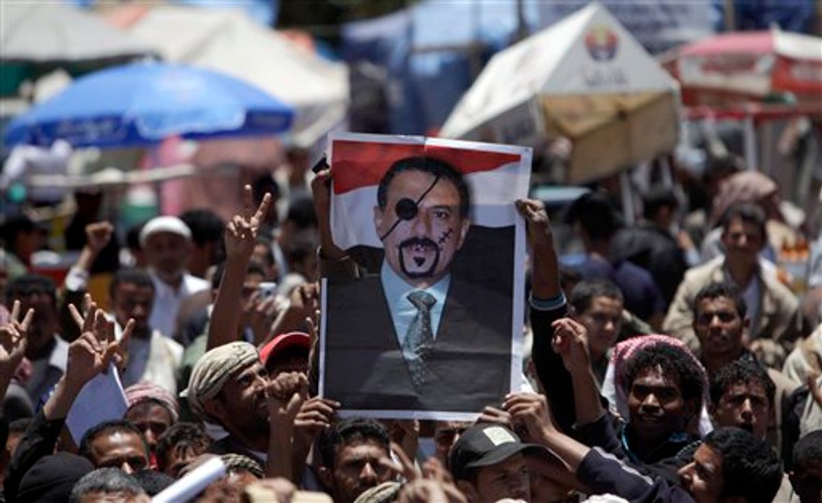 Anti-government protestors hold up a defaced poster of Yemeni President Ali Abdullah Saleh during a demonstration demanding his resignation in Sanaa, Yemen, Wednesday, April 20, 2011. A Yemeni opposition activist said a gunmen on A motorcycle opened fire at hundreds of demonstrators camped out overnight in a western port city, killing at least one and wounding several protesters. (AP Photo/Muhammed Muheisen) (AP)