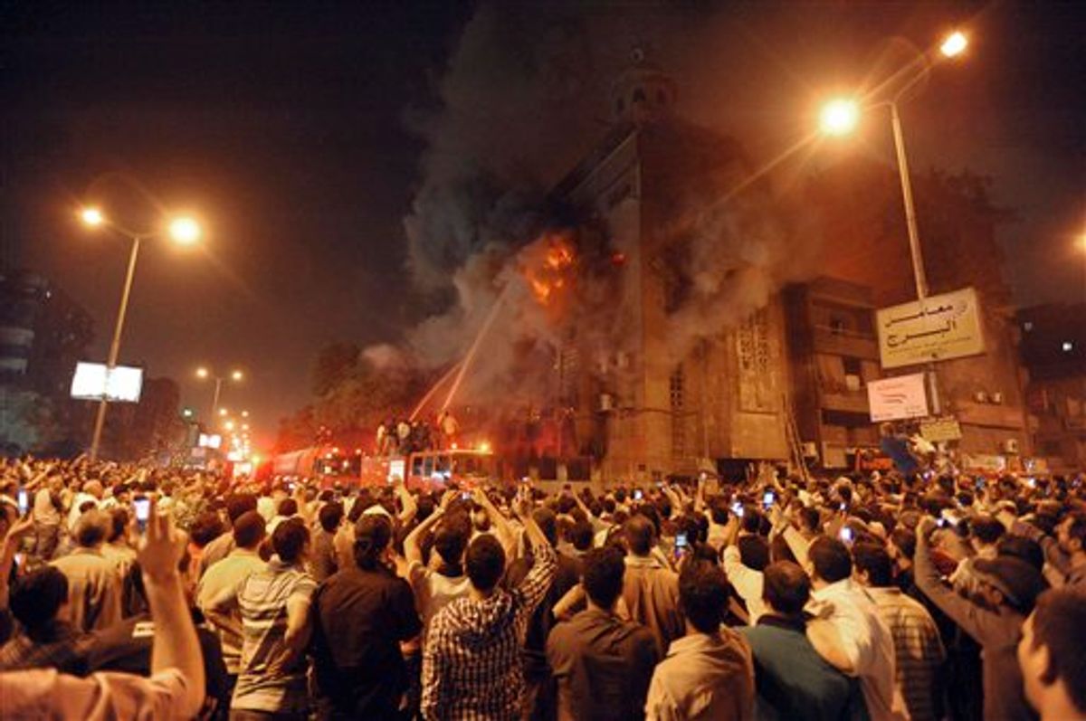 Firemen fight a fire at a church surrounded by angry Muslims in the Imbaba neighborhood in Cairo late Saturday, May 7, 2011. Christians and Muslims fought in the streets of western Cairo in violence triggered by word of a mixed romance, Egypt's official news agency reported. (AP Photo) (AP)