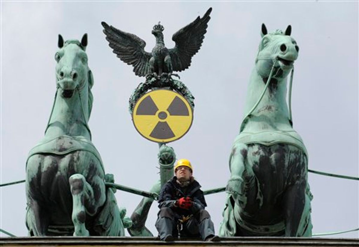 An environmental activist sits on top of the Brandenburg Gate after Greenpeace activists fixed a radioactive sign to the Quadriga in Berlin, Sunday May 29, 2011 to protest against the nuclear power policy of German Government. (AP Photo/dapd/Michael Gottschalk) (AP)