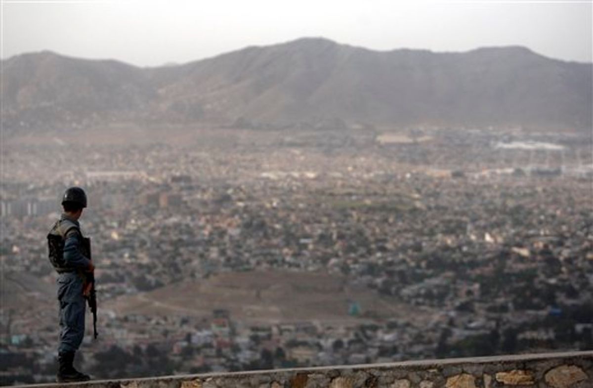 An Afghan policemen stands guard as an aerial view of Kabul city is seen from atop a hill in Kabul, Afghanistan, Friday, May 27, 2011. (AP Photo/Mustafa Quraishi) (AP)