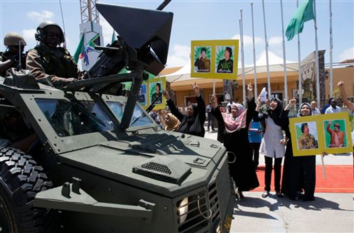 Local residents hold portraits of Libyan leader Moammar Gadhafi and chant as they greet South African security personnel guarding President Jacob Zuma's motorcade leaving the airport in Tripoli, Libya, on Monday, May 30, 2011. (AP Photo/Ivan Sekretarev) (AP)