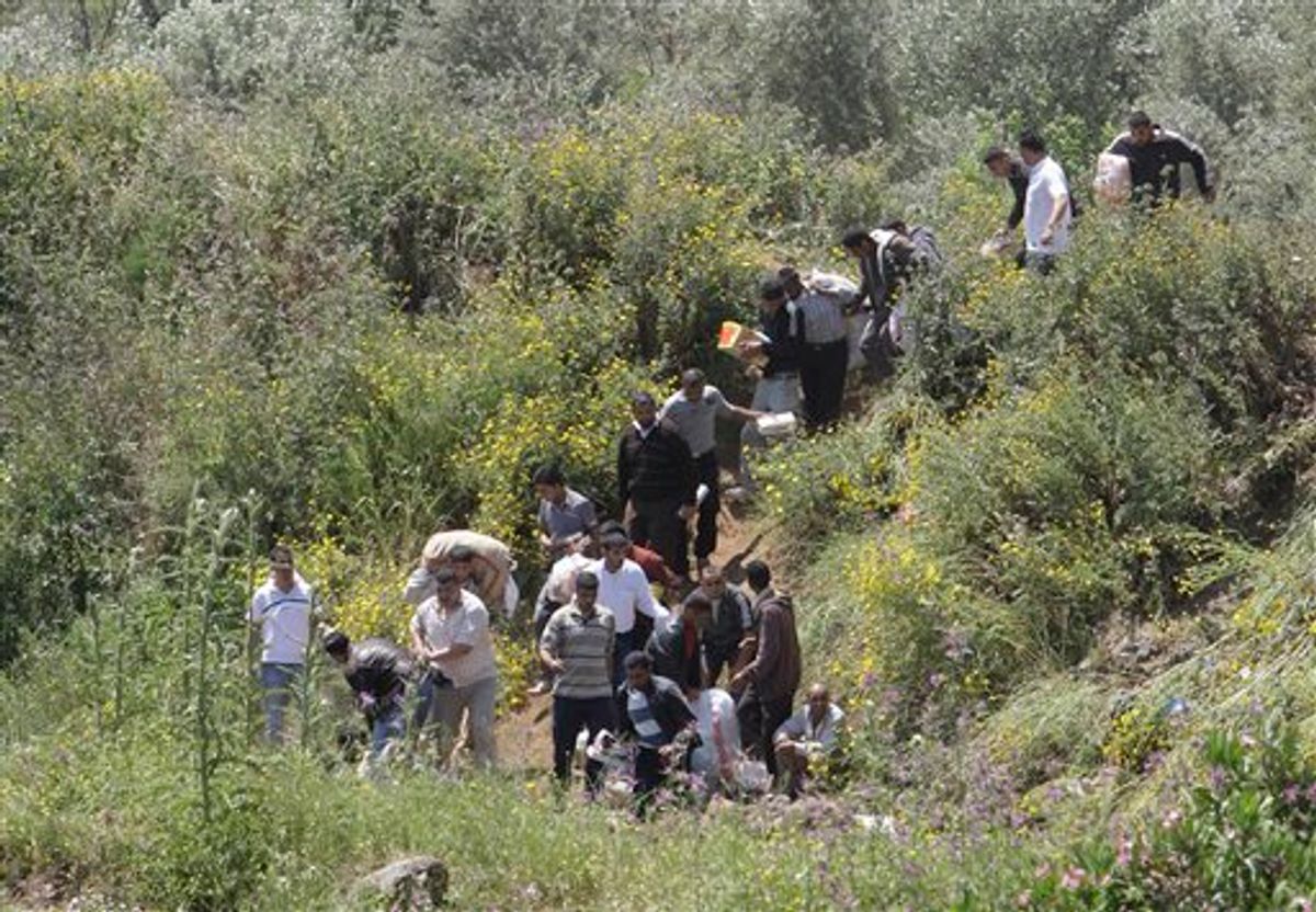 Syrian citizens carry their belongings, as they cross the border illegally , fleeing from violence the western Syrian village of Talkalakh, in the Wadi Khaled area, about one kilometer (0.6 miles) from the Lebanon-Syria border, north Lebanon, Monday May 16, 2011. Carrying mattresses and bags of clothing, Syrians fleeing their homeland described a "catastrophic" scene Monday in a besieged border town that has been largely sealed off as the army tries to crush a two-month uprising. (AP Photo/Bilal Hussein) (AP)