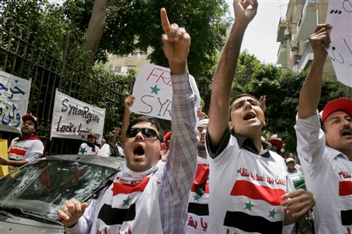 Demonstrators rally against the Syrian regime's crackdown on protesters, outside the Syrian embassy in Cairo, Egypt Tuesday, May 10, 2011. Syrian troops backed by tanks entered several southern villages near the flashpoint city of Daraa on Tuesday, according to an activist, as the Syrian government pressed its efforts to end a nationwide uprising. Writing in Arabic on t-shirts showing the Syrian flag reads "The people want to topple the regime". (AP Photo/Mohammed Abu Zaid) (AP)