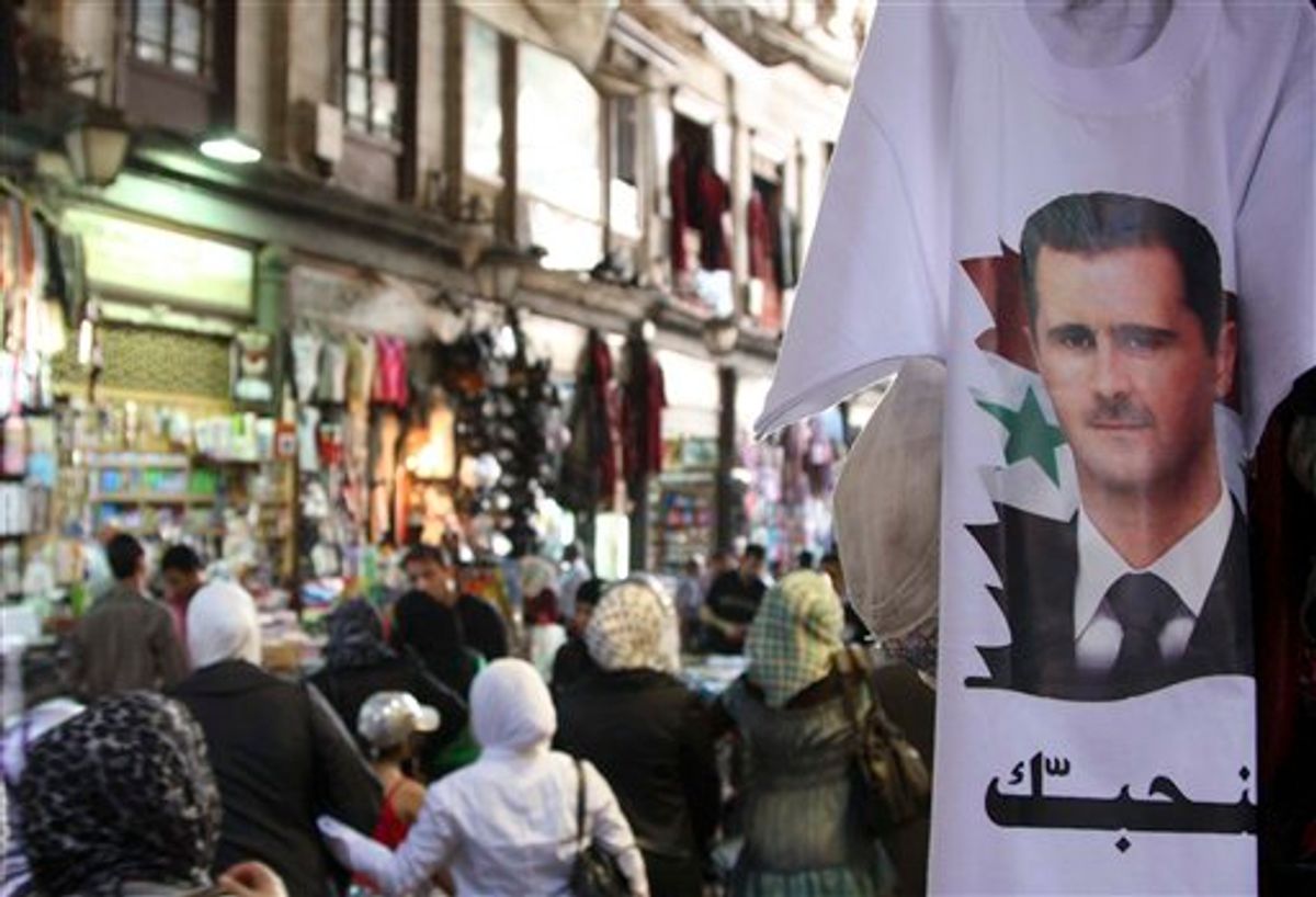Syrians walk past a T-shirt  with a portrait of Syrian President Bashar Assad with an Arabic word read:"we love you," at a popular market in downtown Damascus , Syria, on Monday, May 30, 2011.  Syrian troops shelled a town in the center of the country Monday, and for the first time in the two-month-old revolt against the president, residents armed with automatic rifles and rocket-propelled grenades put up fierce resistance, activists said. State media said four soldiers were killed. (AP Photo/Bassem Tellawi) (AP)