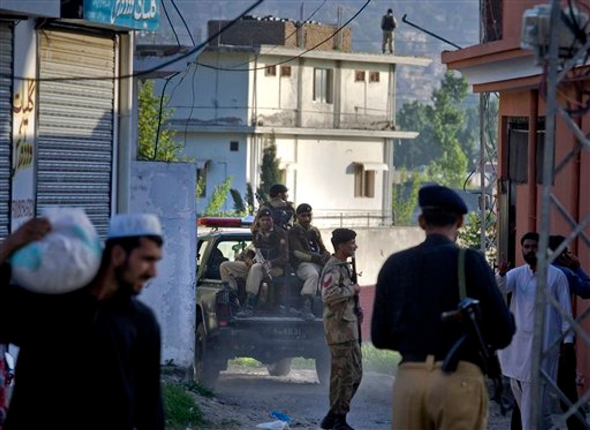 Pakistan army soldiers and police officers patrol past house, background, where it is believed al-Qaida leader Osama bin Laden lived in Abbottabad, Pakistan on Monday, May 2, 2011. Bin Laden, the mastermind behind the Sept. 11, 2001, terror attacks that killed thousands of people, was slain in his hideout in Pakistan early Monday in a firefight with U.S. forces, ending a manhunt that spanned a frustrating decade. (AP Photo/Anjum Naveed) (AP)