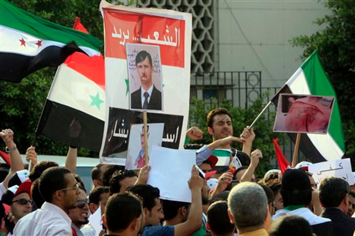 Syrian protesters chant slogans and hold anti-Syrian President posters during a demonstration demanding that Syria's President Bashar Assad step down, in front of the Arab League headquarters building in Cairo, Egypt, Sunday, May 15, 2011. Hundreds of Syrians fled to neighboring Lebanon to escape a violent crackdown against an anti-government uprising that has claimed the lives of more than 800 civilians, Lebanese security officials and a leading human rights group said. Arabic read " people want Assad step down".  (AP Photo/Amr Nabil) (AP)