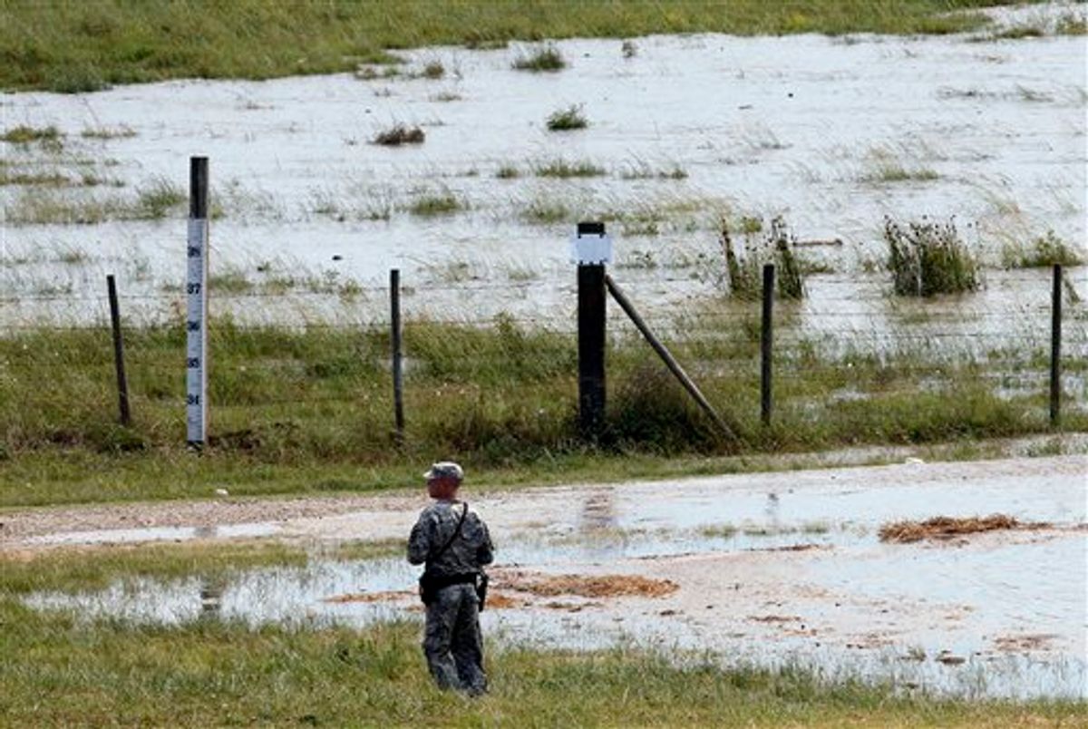 A member of the Louisiana National Guard stands guard as water diverted from the Mississippi River through a bay in the Morganza Spillway begins to fill a pasture in Morganza, La., Saturday, May 14, 2011.   Opening the Morganza spillway diverts water away from Baton Rouge and New Orleans, and the numerous oil refineries and chemical plants along the lower reaches of the Mississippi. (AP Photo/Patrick Semansky)  (AP)