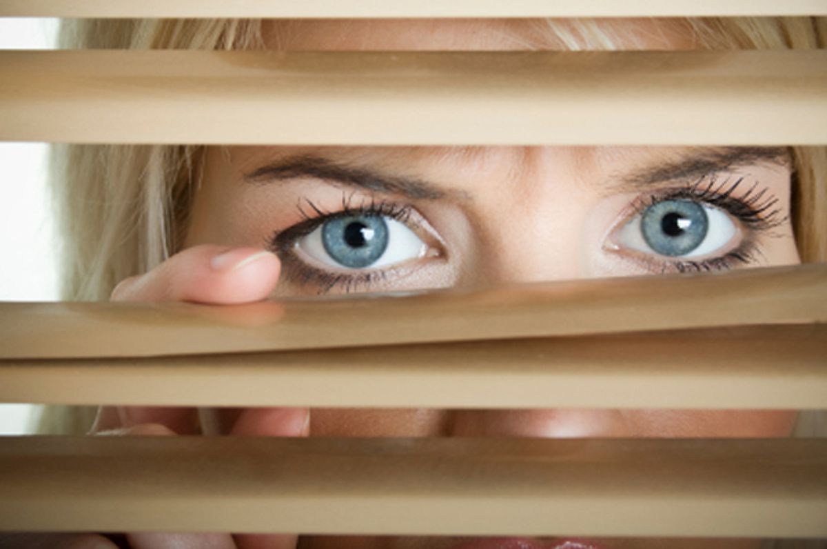 Young scarry women looking through window blinds