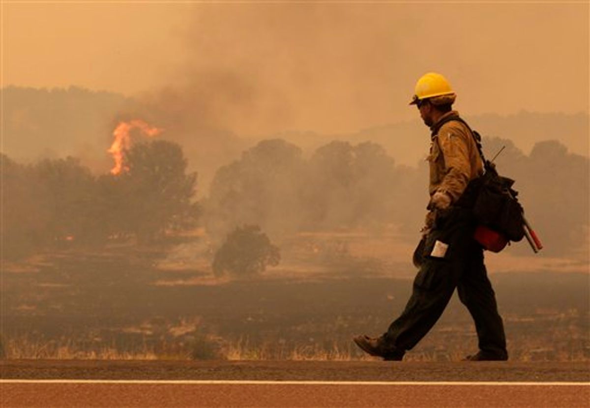 Firefighter Rigoberto Torres, of Orange Cove, Calif., walks along the road while watching a flame during the Wallow fire in the Apache-Sitgreaves National Forest near Springerville, Ariz., Tuesday, June 7, 2011. Officials say the blaze has already burned 486 square miles and winds have been driving the flames 5 to 8 miles a day since the fire began a week ago. (AP Photo/Jae C. Hong)  (AP)